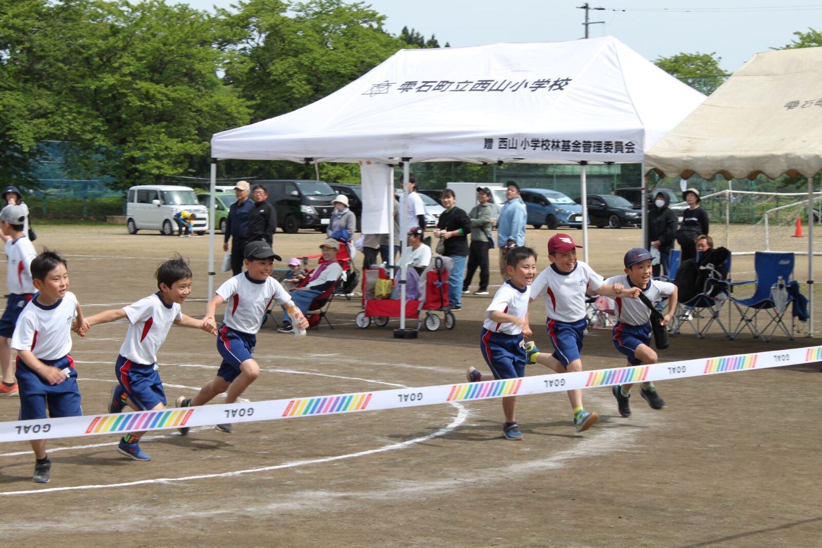 子どもたちが手をつないでゴールテープを駆け抜ける様子